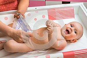 Mother changing diaper to her little baby girl