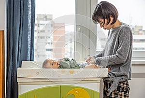 Mother changing diapers to hers newborn son