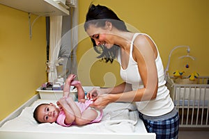 A mother changing her baby nappy .