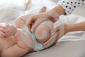 Mother changing her baby`s diaper on bed