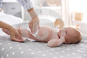 Mother changing her baby`s diaper on bed