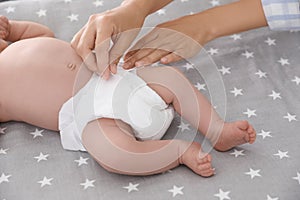 Mother changing her baby`s diaper on bed