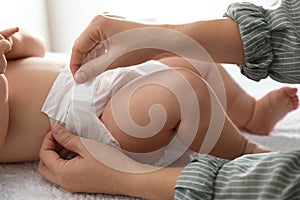 Mother changing her baby`s diaper on table