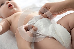 Mother changing her baby`s diaper on table