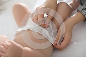 Mother changing her baby`s diaper on table
