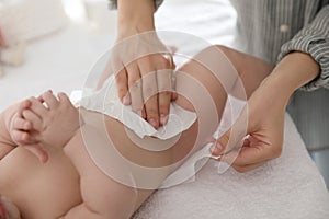 Mother changing her baby`s diaper on table photo