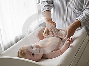 Mother changing her baby`s diaper on the table. Motherhood concept. Child hygiene