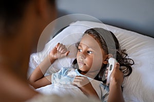 Mother checking daughter temperature with ear thermometer