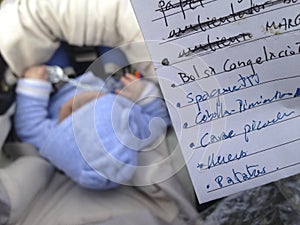 Mother checking the shopping list while she is pushing her baby