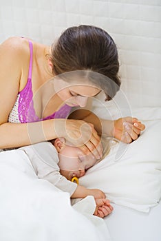 Mother checking temperature of forehead of baby