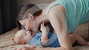 Mother and child on bed. Mom and baby boy in diaper playing in sunny bedroom. Parent and little kid relaxing at home