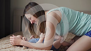Mother and child on bed. Mom and baby boy in diaper playing in sunny bedroom. Parent and little kid relaxing at home