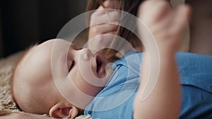 Mother and child on bed. Mom and baby boy in diaper playing in sunny bedroom. Parent and little kid relaxing at home