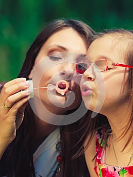 Mother and child blowing soap bubbles outdoor.