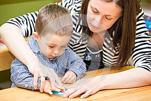 Madre a chico dibujo común lapices en jardín de infancia sobre el mesa en jardín de infancia 