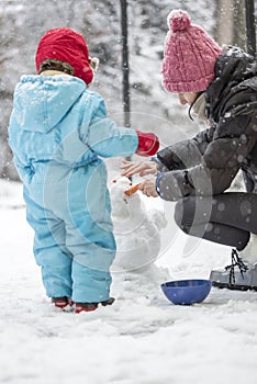 Mother and child building a winter snowman