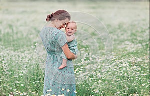 Mother and child in a chamomile field in summer. Maternal love tenderness care. Motherhood is happiness emotionally. Natural eco.