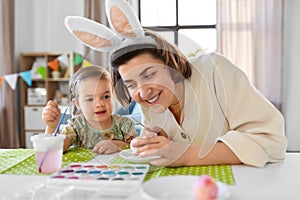 mother with child coloring easter eggs at home