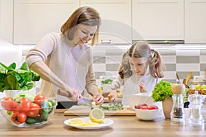 Mother and child cooking together at home in kitchen. Healthy eating, mother teaches daughter to cook, parent child communication