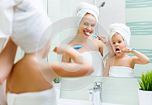 Mother and child daughter brush their teeth with toothbrush