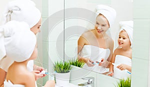 Mother and child daughter brush their teeth with toothbrush