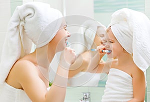 Mother and child daughter brush their teeth with toothbrush