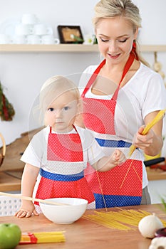 Mother and child daughter cooking pasta or salad for the breakfast. Concept of happy family in the kitchen