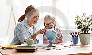 Mother and child daughter doing homework geography with globe