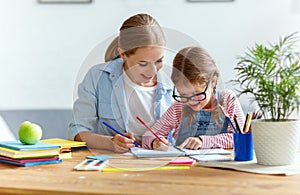 Mother and child daughter doing homework writing and reading at