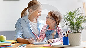 Mother and child daughter doing homework writing and reading at