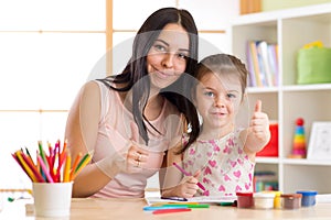 Mother and child daughter draw together with pencils at table