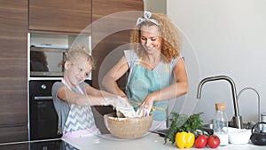 Mother and child daughter girl having fun while making dinner at the kitchen.