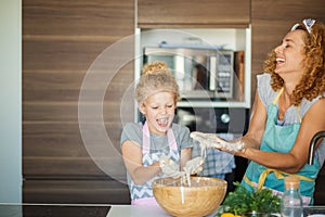 Mother and child daughter girl having fun while making dinner at the kitchen.