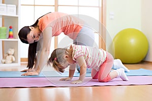 Mother and child daughter practicing yoga together at home. Sport and family concept