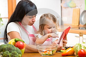 Mother and child daughter prepare recipe in kitchen.