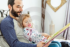 A mother and child daughter reading book in bed before going to sleep