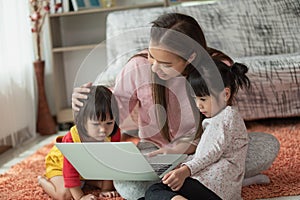 Mother and child daughter using laptop computer together in her house, education concept