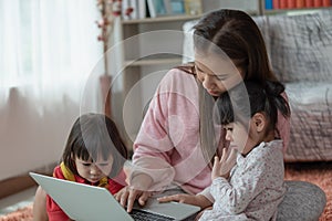 Mother and child daughter using laptop computer together in her house, education concept