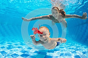 Mother with child dive underwater in swimming pool