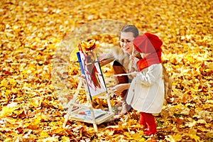 Mother and child drawing on easel in autumn park. Creative kids