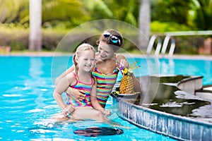 Mother and child drink juice in swimming pool