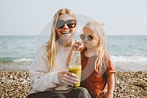 Mother and child drinking detox kiwi smoothie summer family vacations on beach healthy lifestyle