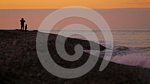 Mother and child enjoying view of peaceful sea, walking on the beach at sunset