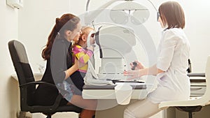 Mother with child in eye clinic - children ophthalmology - optometrist Checks Child`s Eye