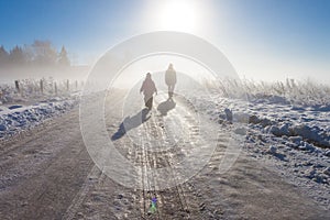 Mother and child on foggy snow farm road