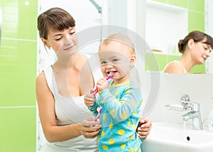 Mother with child girl brushing teeth