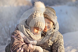 Mother and child girl having fun, playing and laughing on snowy winter.