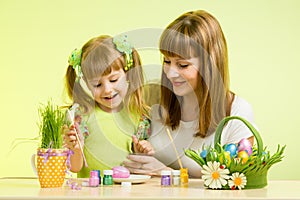 Mother and child girl paint eggs preparing to Easter holiday