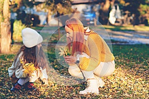 Mother and child girl playing with autumn leaves. Happy family enjoying autumn day together