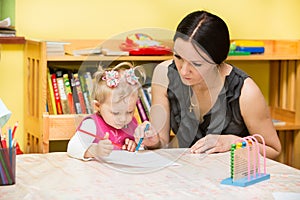 Mother and child girl playing in kindergarten in Montessori Class.